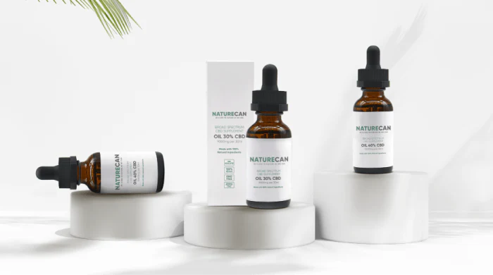 Three Naturecan broad-spectrum CBD oil bottles – two at 40% CBD and one at 30% CBD with its white packaging box – displayed on white cylindrical pedestals against a clean white background