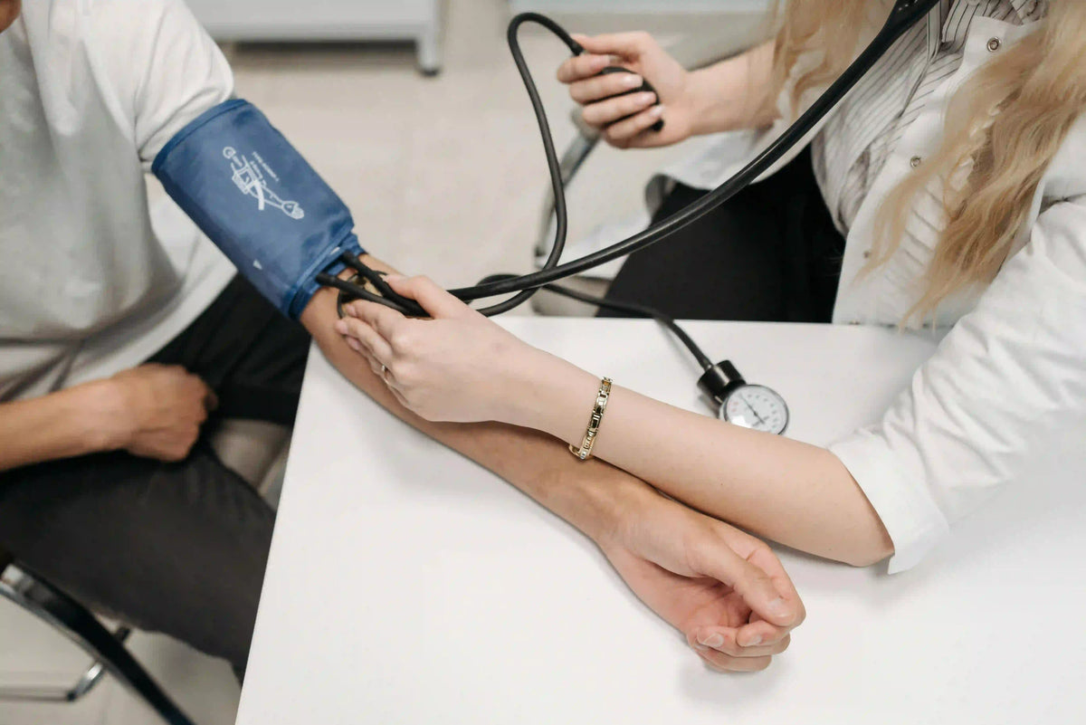 Healthcare professional's hands measuring a patient's blood pressure with a manual cuff and sphygmomanometer