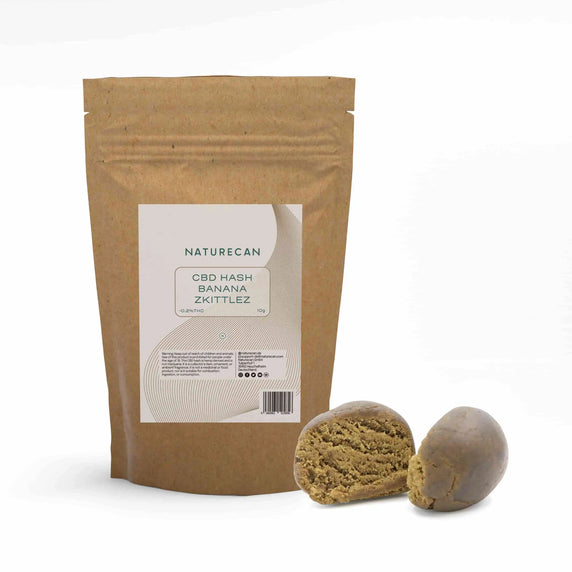 Naturecan CBD Hash Banana Zkittlez – kraft paper resealable pouch 10g, <0.2% THC, with two rounded pieces of light brown CBD hash beside it