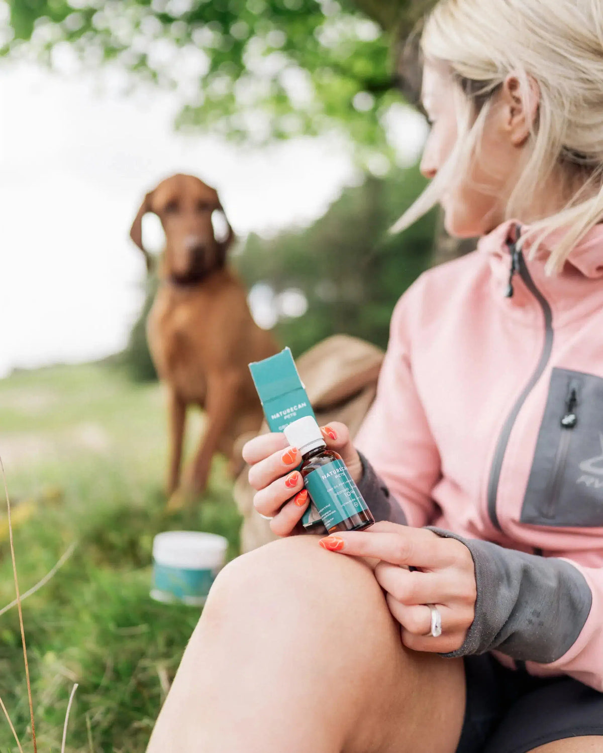 Lady holding our CBD oil for Dogs with a dog in the background