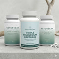 Naturecan Welcome Essentials Bundle – three white supplement bottles on stone surface with driftwood background: Algae Omega-3, Triple Magnesium Capsules (100% NRV high bioavailability 30 servings), and Vitamin D3 and K2 (30 tablets); with white tablets scattered beside them